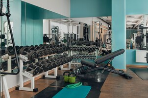 Un gimnasio con racks para pesas, kettlebells y equipamiento de ejercicio.
