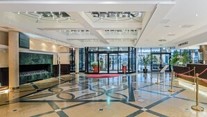 A modern lobby with a glass entrance, a marble fireplace, and a patterned floor. - Holiday Club Turun Caribia Superior Apartments (Turku)