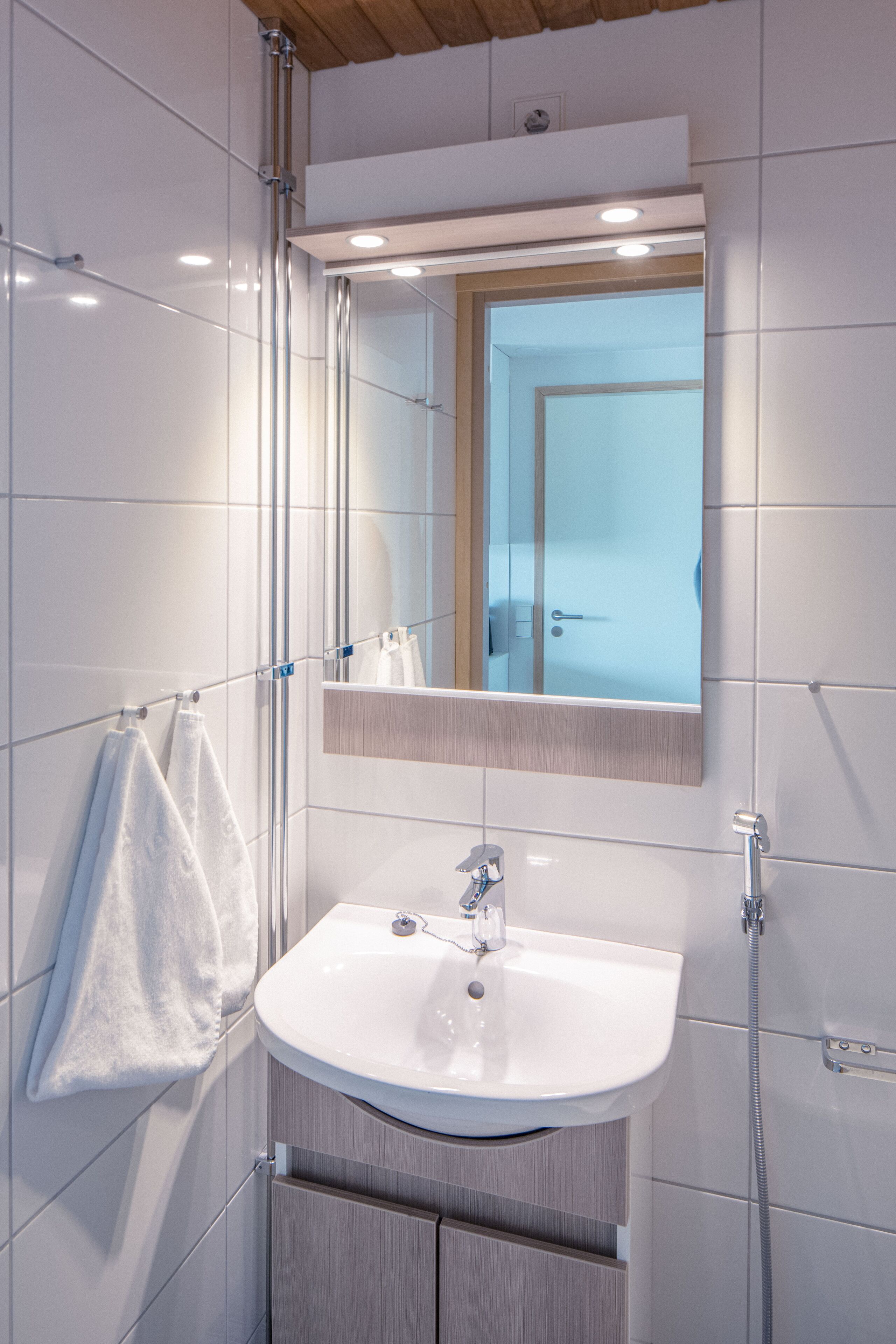 Une salle de bain moderne avec un lavabo blanc, un miroir et un porte-serviettes.