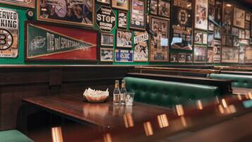 A restaurant with a wall of framed sports memorabilia and a wooden table with a basket and glasses.