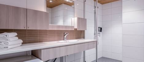 A modern bathroom with a built-in washing machine, a sink, and a shower area.