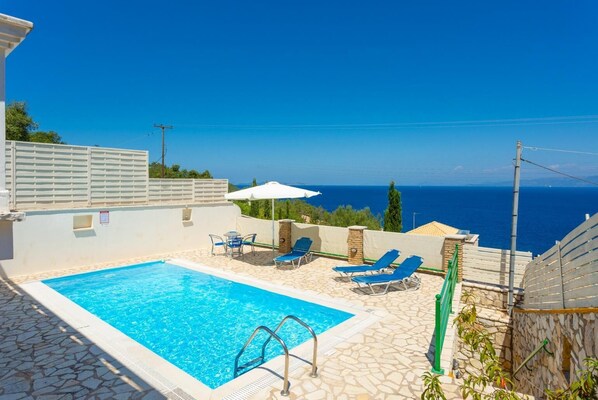 A swimming pool with lounge chairs and a view of the sea.
