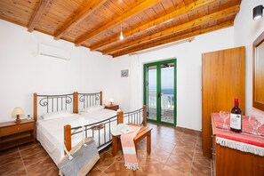 A bedroom with a bed, bedside tables, a bench, a bottle of wine, and a view through a green door.