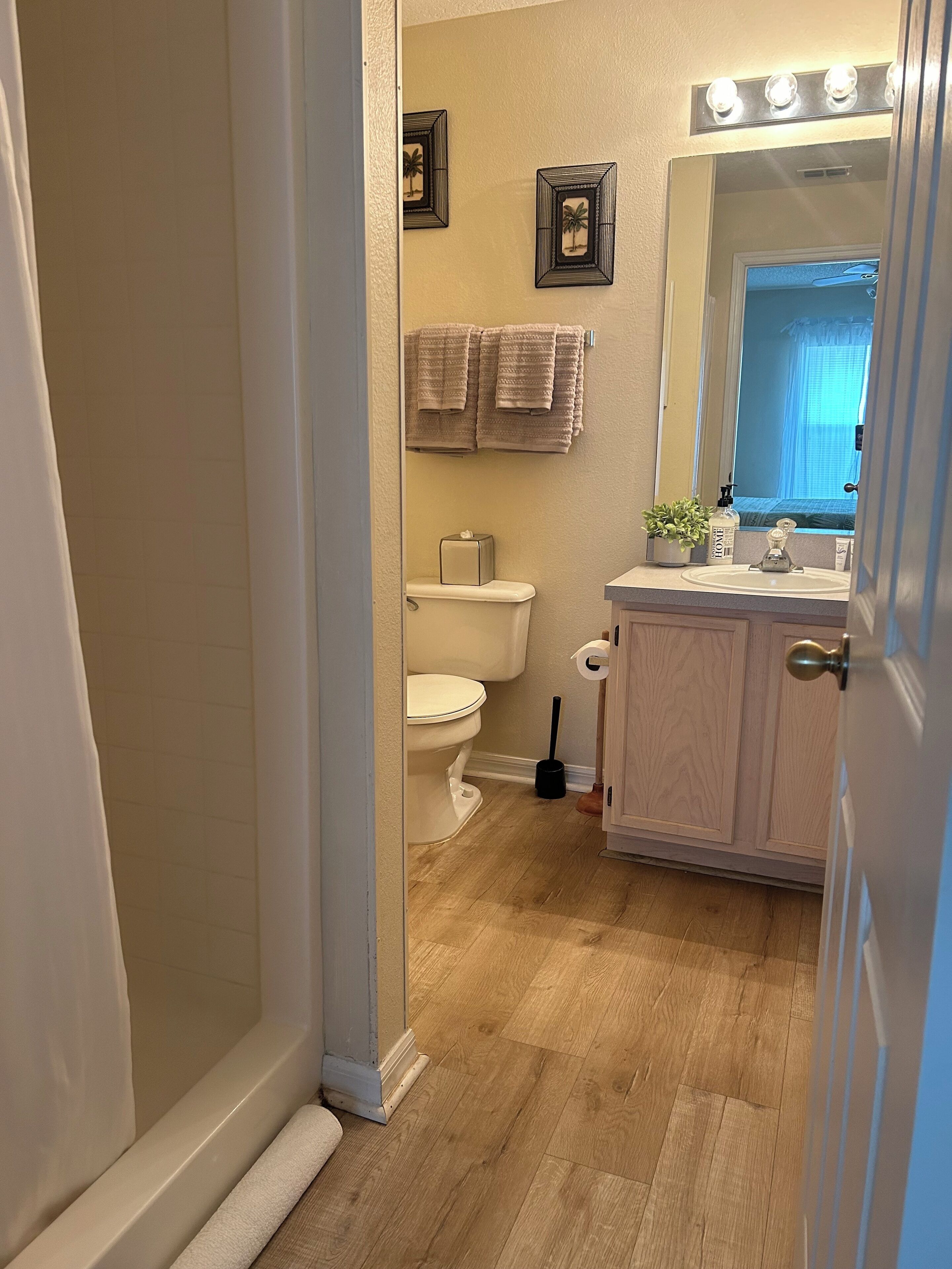 A bathroom with a toilet, sink, and vanity. There are towels hanging on the wall and a mirror above the sink.