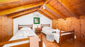 A cozy attic bedroom with two wooden beds, a small table, and a wall-mounted air conditioner. - Villa Anastasia - Three Bedroom Villa, Sleeps 6 (Paxi)