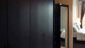 Ein Hotelzimmer mit großem Kleiderschrank, einem Bett mit weißer Bettwäsche und einem Fenster mit Vorhängen.