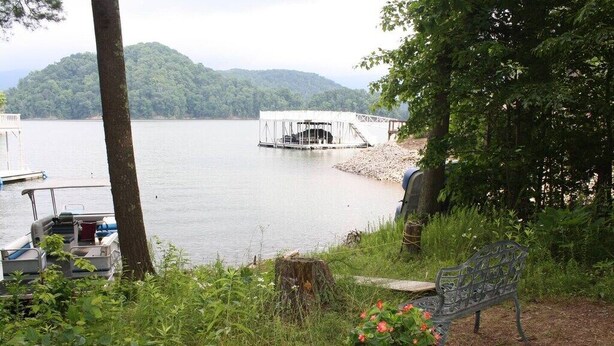 A lakeside view with a dock, a covered boat launch, and a bench with a flower pot. - Paradise Peak - Tranquility and majestic splendor! (Butler)