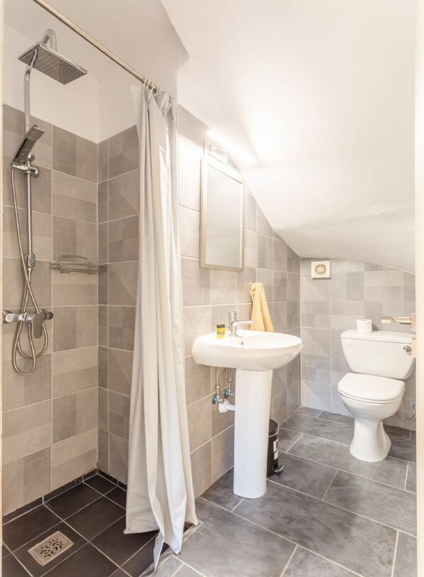 A bathroom with a shower, sink, and toilet.