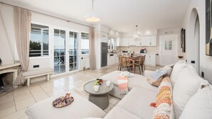A spacious living area with a large sofa, a dining table, and a kitchen in the background.