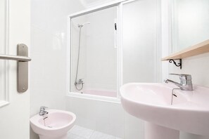 Une salle de bain avec douche, bidet et deux lavabos.