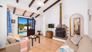 A spacious living room with a fireplace, a pool view, and a cozy seating area. - Villa Ca Nostra - Three Bedroom Villa, Sleeps 6 (Cala en Porter)