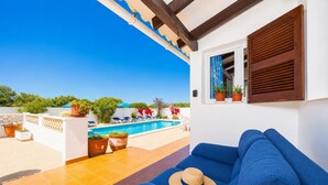 A blue sofa with a straw hat, a pool, and potted plants on a terrace. - Villa Ca Nostra - Three Bedroom Villa, Sleeps 6 (Cala en Porter)