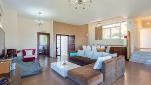 Ein geräumiges Wohnzimmer mit einer großen Eckcouch, einem Couchtisch und einem Essbereich mit Tisch und Stühlen.