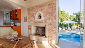 Un salon avec une cheminée, une piscine et une vue sur l’extérieur.