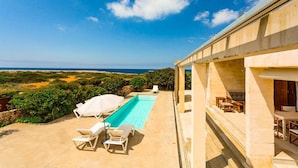 Ein Poolbereich mit Liegestühlen und Blick auf das Meer.