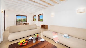 Ein geräumiger Wohnbereich mit zwei Sofas, einem Couchtisch mit Früchten und einem Essbereich mit Tisch und Stühlen.
