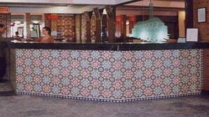 A reception area with a patterned wall, a reception desk, and a sign indicating the reception. - Batha (Fes)