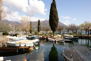 Un port de plaisance avec des bateaux amarrés, des arbres et des montagnes en arrière-plan.