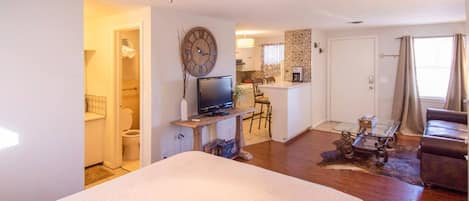 A compact living space with a bed, a TV, a small kitchen, and a dining area.