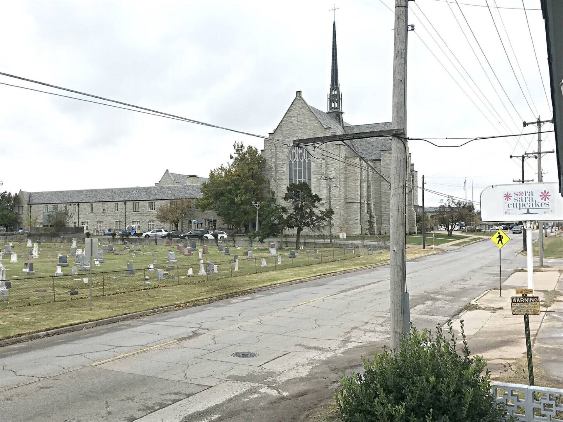 A cemetery with headstones, a church with a tall steeple, and a sign for 'sara cupcakes'.