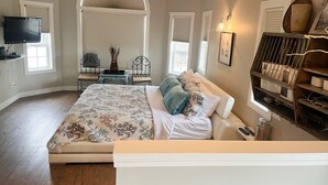 A bedroom with a large bed, a TV, a desk, and a shelving unit. - Ultimate Pool House – 5 Kings, Near Beach and Wineries (Penticton)