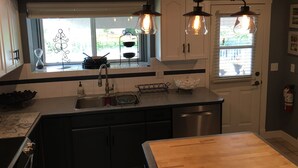A modern kitchen with a central island, stainless steel appliances, and pendant lighting. - Ultimate Pool House – 5 Kings, Near Beach and Wineries (Penticton)