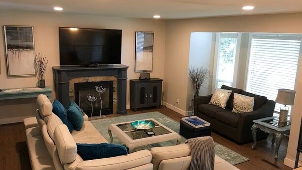 A living room with a fireplace, sofa, TV, and a coffee table. - Ultimate Pool House – 5 Kings, Near Beach and Wineries (Penticton)
