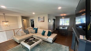 A modern living room with a sectional sofa, a coffee table, and a dining area with a table and chairs. - Ultimate Pool House – 5 Kings, Near Beach and Wineries (Penticton)