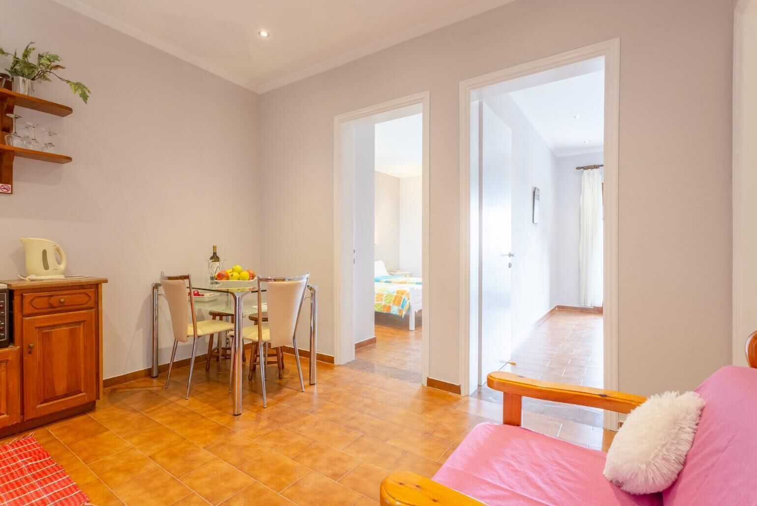 A compact living space with a dining area, a kitchenette, and a bedroom visible through an open door.