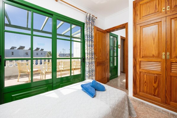 Une chambre avec un lit, une vue sur les bâtiments environnants et une porte en bois.