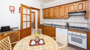 Una cucina compatta con mobili in legno, un piano di lavoro in granito e un'area pranzo con tovaglia fantasia.