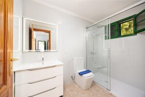 A bathroom with a white vanity, a glass shower enclosure, and a toilet.