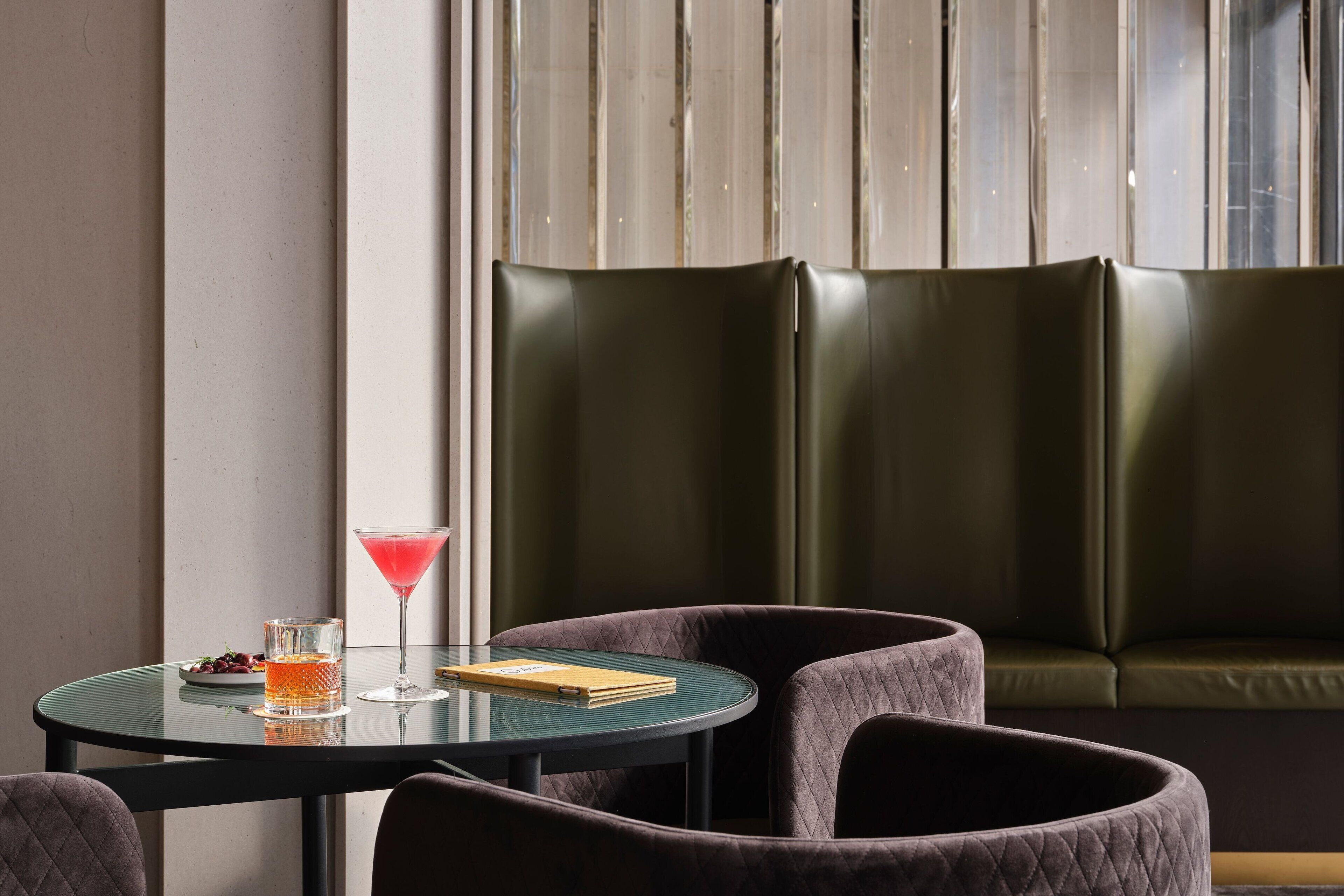 Een moderne zithoek met een ronde tafel, een martini glas en een notitieboek.