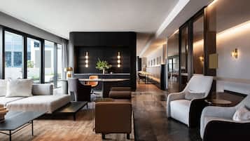 Un moderno vestíbulo de hotel con un sofá, sillones, una zona de comedor y una recepción.
