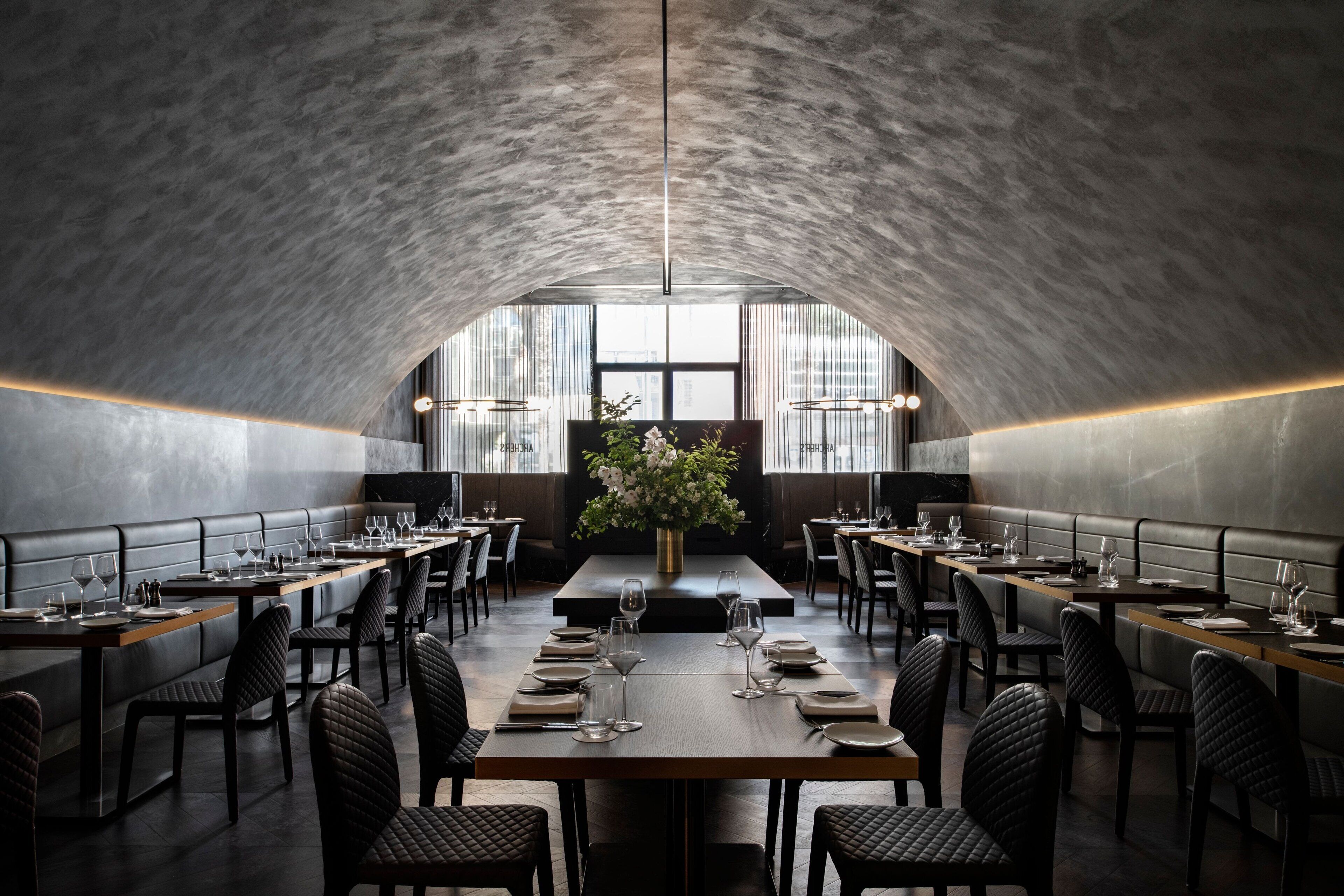 A restaurant with a high, arched ceiling and long tables set for dining.