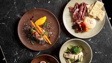Three plates of food on a dark marble table.