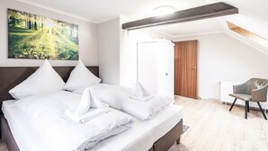 A bedroom with a large bed, a chair, a painting, and a door leading to another room. - A beautiful home (Gernrode)