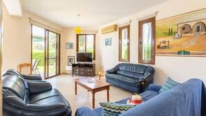 A living room with a sofa, a coffee table, and a TV stand. - Villa Halima Fostira (Poli Crysochous)