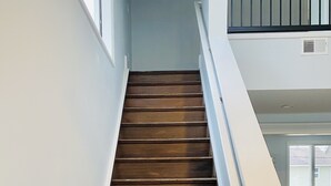 Un escalier en bois, avec des murs blancs et une fenêtre en haut.