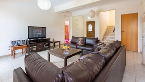 Una sala moderna con un sofá de cuero, una mesa de centro, un televisor y una escalera que lleva a otra habitación.