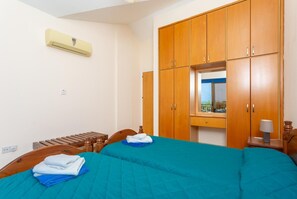Une chambre d’hôtel avec deux lits, des armoires en bois, une fenêtre avec vue et un appareil de climatisation.