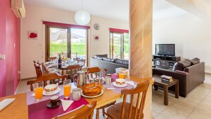 Un comedor con una mesa dispuesta para el desayuno, un sofá y un televisor en la sala.