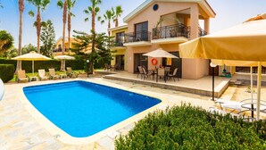 Un hotel con piscina, mobiliario exterior y palmeras.