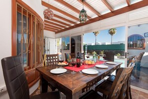A dining area with a wooden table set for four, surrounded by chairs.