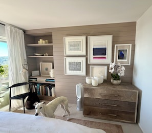A modern bedroom with a bed, a dog, a bookshelf, a dresser, and framed artwork on the wall. - Beautiful Tiburon Apt WIth Breathtaking Views Of The Bay (Tiburon)