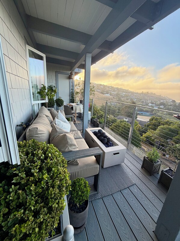 A balcony with a sofa, potted plants, and a view of a cityscape.