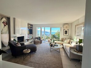 A modern living room with a fireplace, seating area, and a view of the city. - Beautiful Tiburon Apt WIth Breathtaking Views Of The Bay (Tiburon)