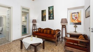 A cozy living room with a sofa, a coffee table, and two lamps. There are paintings on the wall and a door leading to a bathroom. - Villa Maro Large Private Pool, A/C, WiFi (Kefalas)