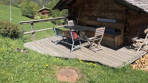 Una cabaña de madera con un porche, una mesa y sillas.