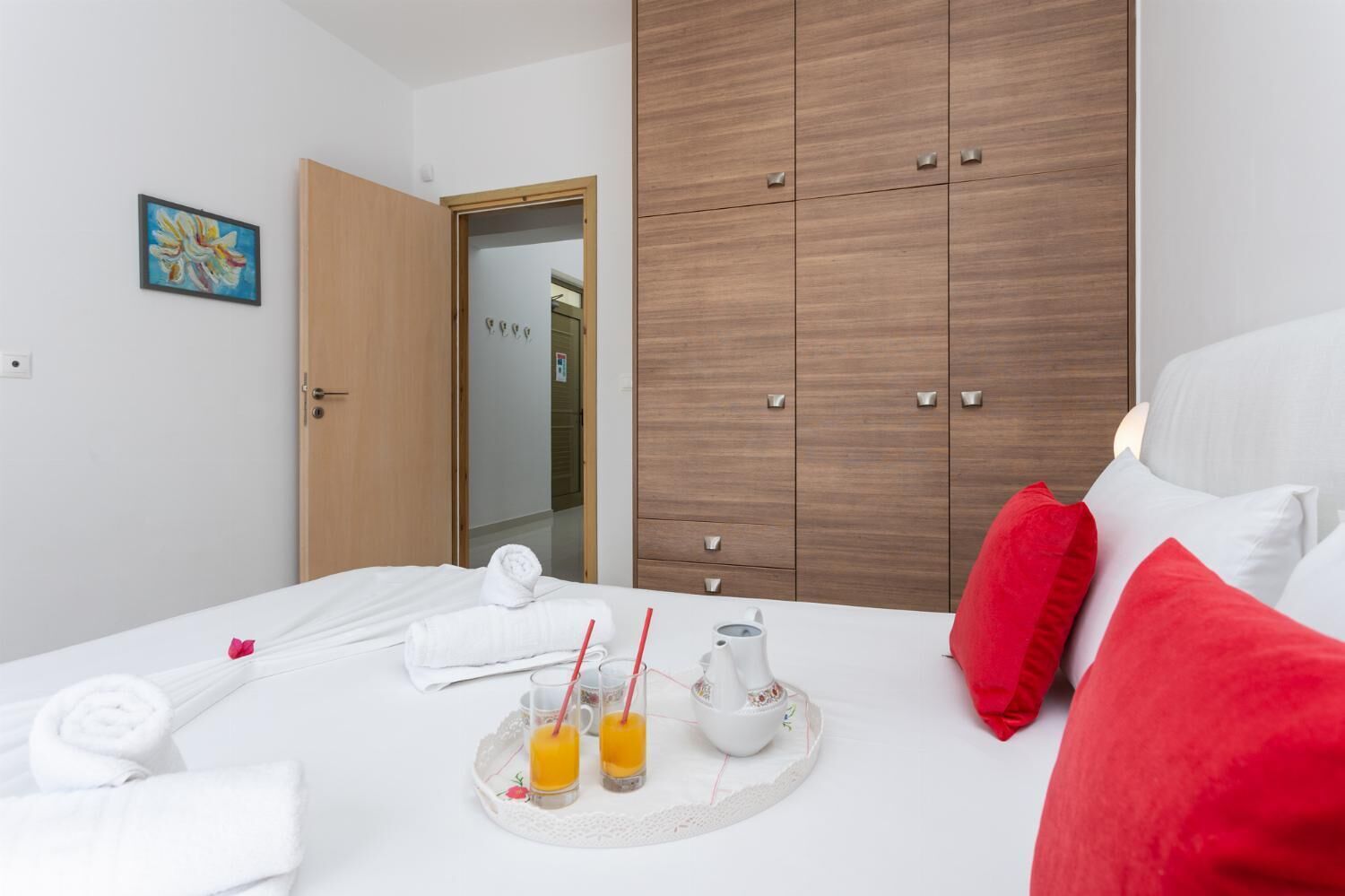 Ett hotellrum med en säng, en garderob, en tavla och ett bricka med apelsinjuice och en vattenkokare.